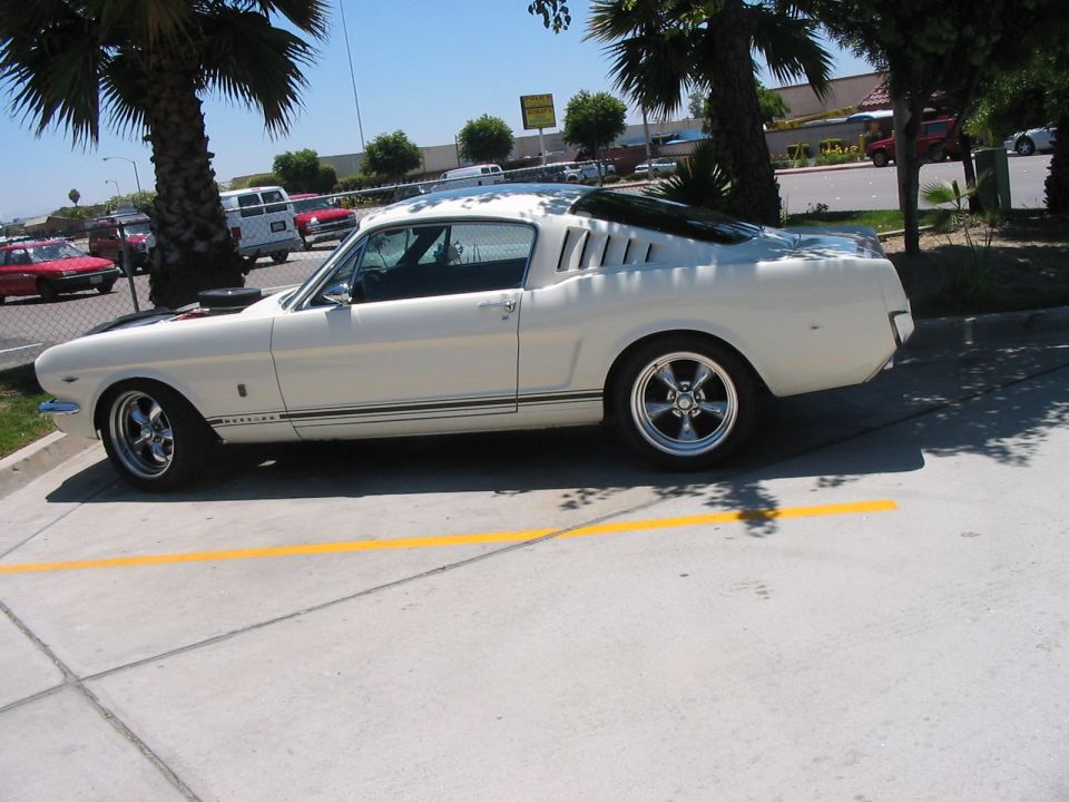 White 1965 coupe with black hood stripes and louvers on rear quarter windows
