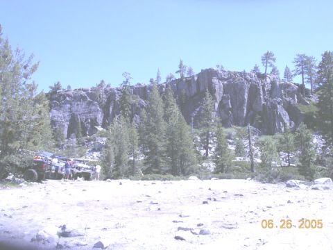 1994 Ford Bronco - A group of off-road vehicles are parked in a scenic, rocky landscape with a large cliff and trees.