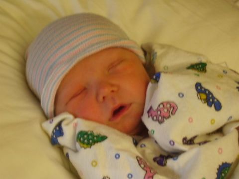 1979 Ford F-150 - A newborn baby sleeps soundly, wrapped in a hospital hat and a swaddle blanket with colorful dinosaur prints.
