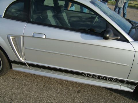 1998 Ford Taurus - A silver Ford Mustang is shown from the side, a black stripe and 'MUSTANG' badging on the lower body.
