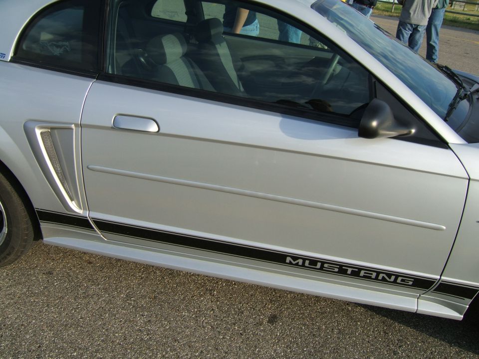 Silver Ford Mustang side view with black stripe and 'MUSTANG' text on the rocker panel