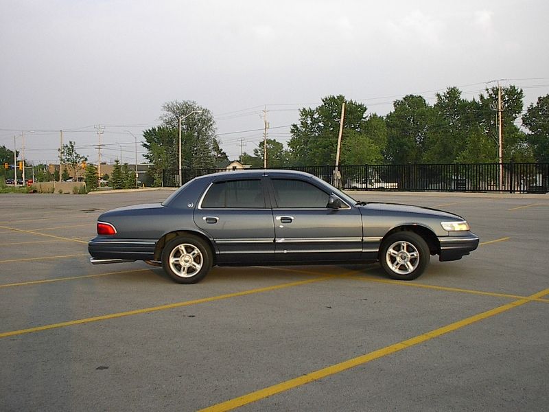 Slate blue Mercury Grand Marquis sedan side profile in an empty parking lot