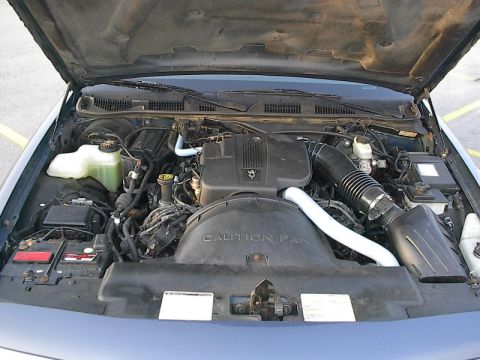 1985 Mercury Grand Marquis - The engine bay of a vehicle, the V8 engine, air intake system, and coolant reservoir under the hood.