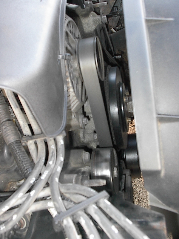Close-up of serpentine belt, crank pulley and tensioner in an engine bay