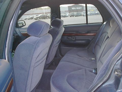 1985 Mercury Grand Marquis - The interior of a car shows plush blue seats and a view of a Walmart parking lot through the windows.