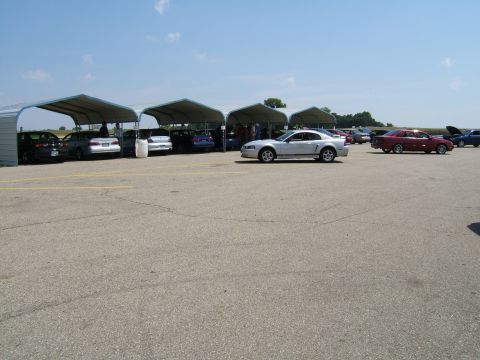 1998 Ford Taurus - Silver coupe with racing stripes parked on asphalt, side view. Several cars are parked under canopies in the background.
