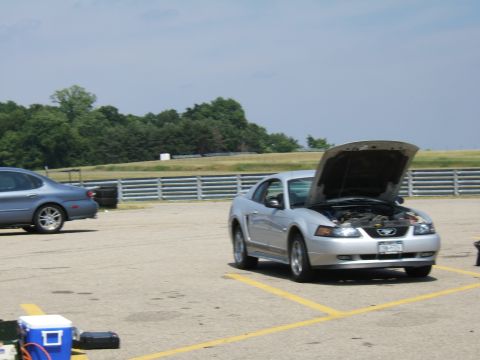 1998 Ford Taurus - A silver coupe sits with its hood open on a sunny day at a track, with another car visible in the background.