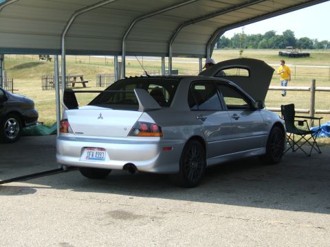 1998 Ford Taurus - A silver Mitsubishi Lancer Evolution VIII is parked under a shelter, its hood open, with a second vehicle partially visible to the left.