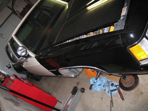 1991 Ford LTD Crown Victoria - A black and tan police car is undergoing maintenance in a garage, with its hood open and parts scattered around.