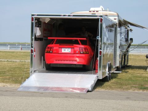 1998 Ford Taurus - A red Ford Mustang with a spoiler is being loaded into a trailer, with a motorhome attached.