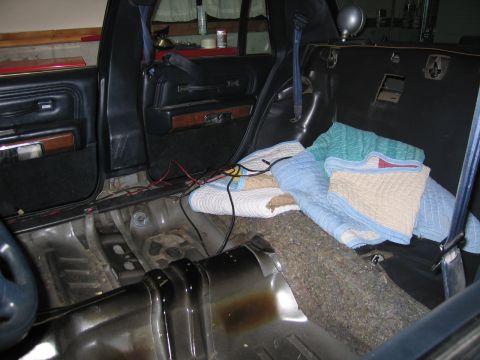 1991 Ford LTD Crown Victoria - The interior of a car shows exposed metal and removed carpet, with blankets covering the rear seat.