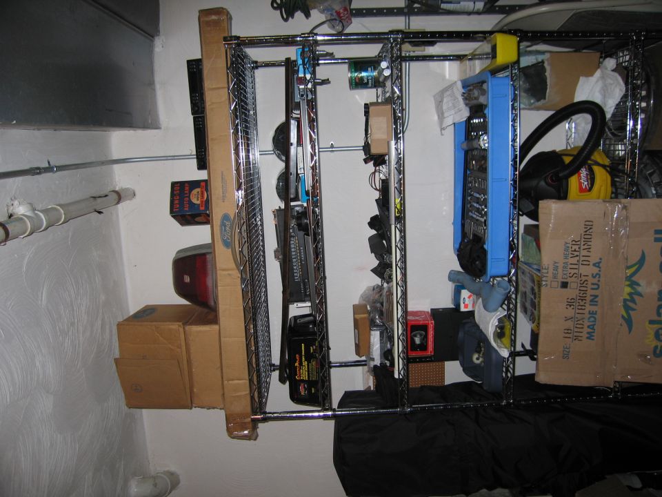 Storage shelves filled with tools, boxes, and car parts in a garage