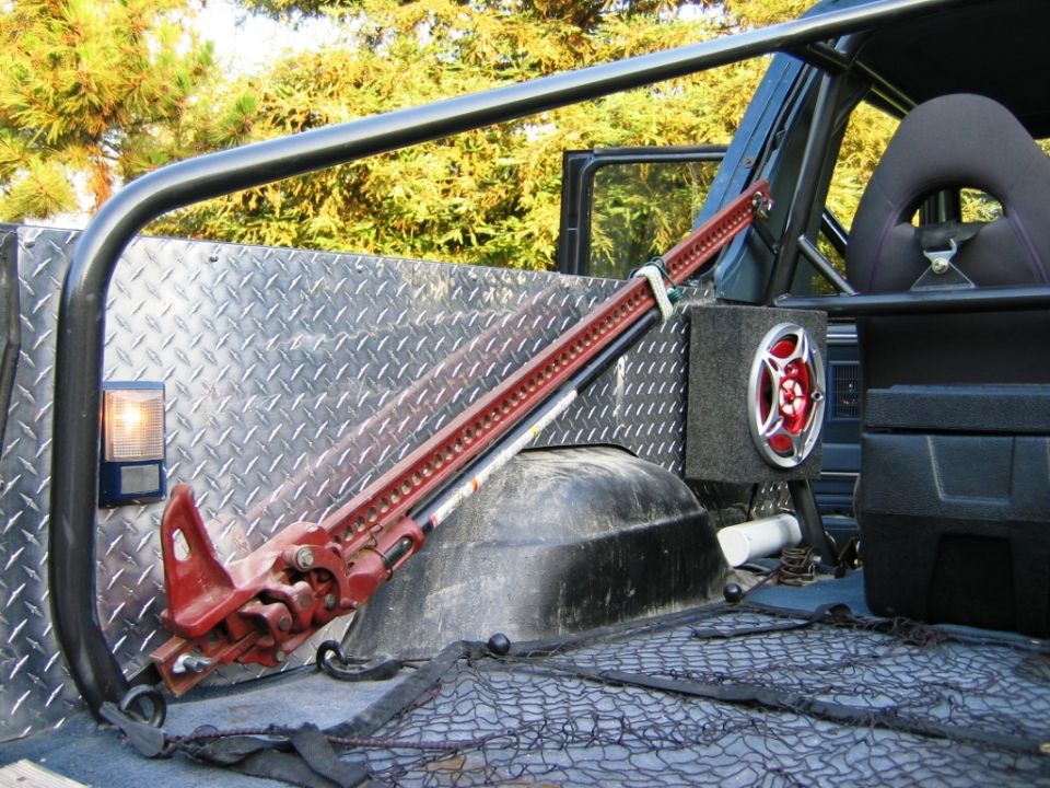 Diamond-plate interior with red Hi-Lift jack, roll cage, and mounted speaker