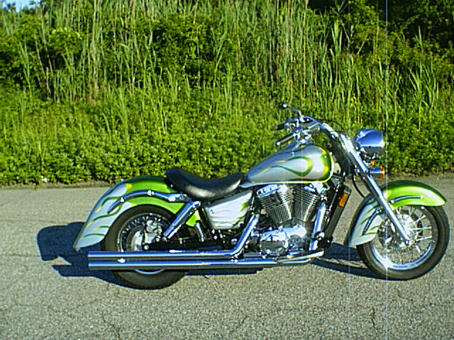 Silver cruiser motorcycle with green flame graphics, side view on pavement