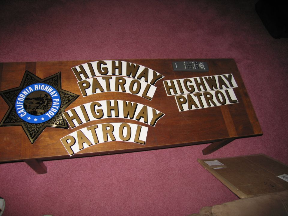 California Highway Patrol star badge and several pieces of 'HIGHWAY PATROL' lettering on a wooden table