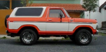 1979 Ford Bronco - This two-tone orange and white Ford Bronco from 1979 is seen from the side, its iconic body style and a rear-mounted spare tire.