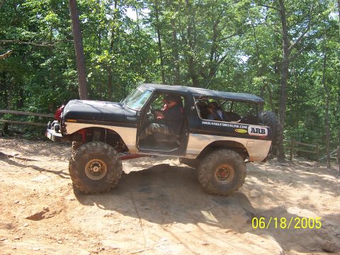 1978 Ford Bronco - Modified 1978 Ford Bronco navigating an off-road trail with trees in the background.