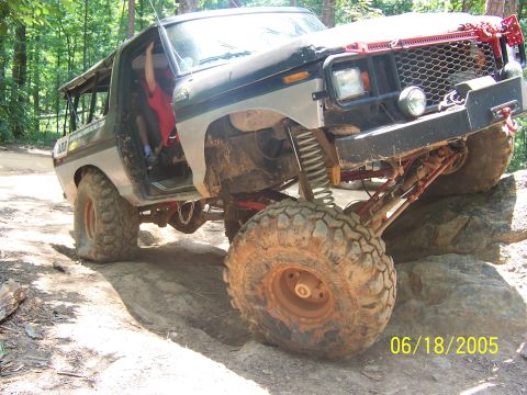 1978 Ford Bronco - Off-road 1978 Ford Bronco navigating rocky terrain with its driver's door open.