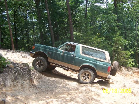 1978 Ford Bronco - This SUV is navigating a challenging off-road trail with steep inclines and loose dirt.