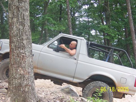 1978 Ford Bronco - A man drives a white SUV with a roll cage over rough terrain, captured on June 18, 2005.