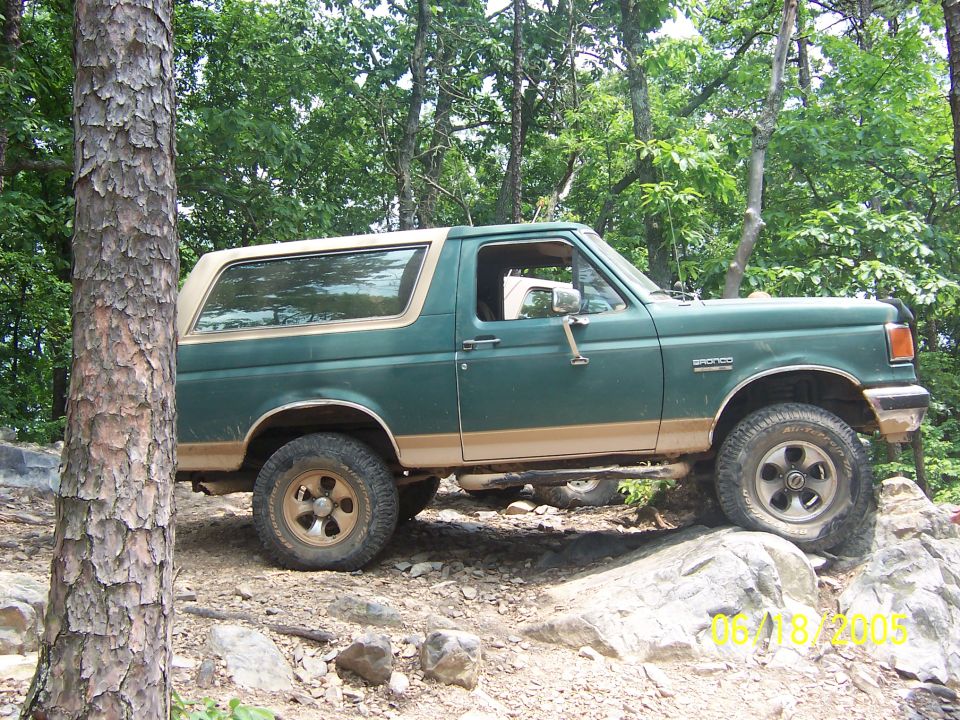 Green Ford Bronco with tan trim on rocky terrain