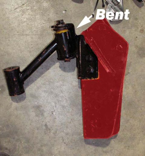 1988 Ford Bronco - A close-up view of a damaged automotive suspension part, with text indicating it is bent.