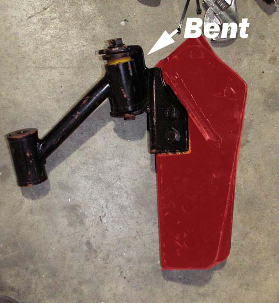 Bent black metal suspension component with a red piece attached. Arrow points to bent area