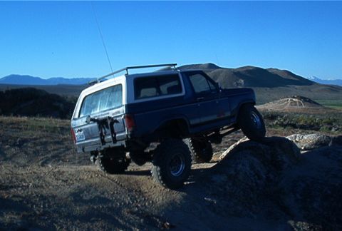 1986 Ford Bronco - This Ford Bronco is navigating a rocky terrain under a clear blue sky.