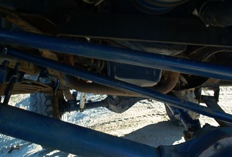 1986 Ford Bronco - The underside of a vehicle shows its suspension, steering, and exhaust system components.