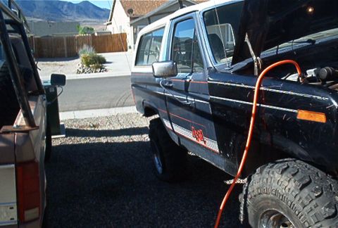 1986 Ford Bronco - 1986 Ford Bronco with hood open, jumper cables attached, parked next to another vehicle in a driveway.
