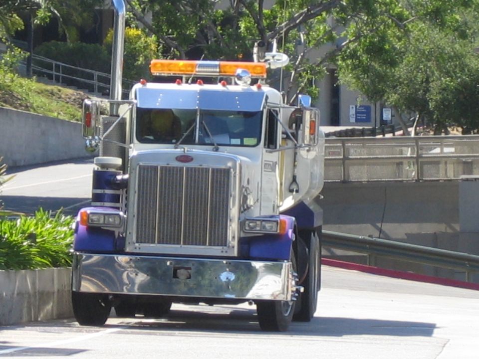Front view of a chrome-grille Peterbilt water truck driving on a ramp
