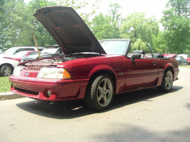Red 1993 Ford Mustang convertible with hood open, showing the engine. The car has a black interior and is parked outdoors