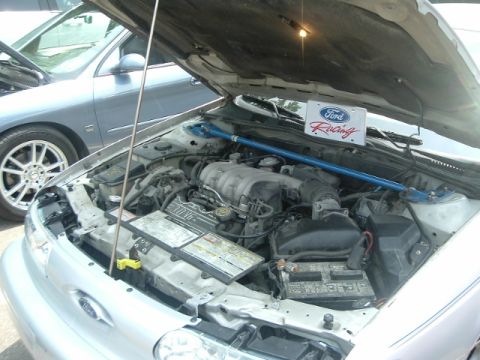 1993 Ford Taurus - The engine bay of a 1993 Ford Taurus is displayed, complete with a Ford Racing sign and a blue strut bar.