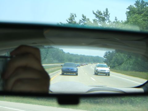 1998 Ford Taurus - A blue sedan is seen driving on a highway, reflected in the rearview mirror of another vehicle.