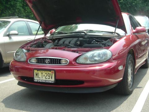 1993 Ford Taurus - The front of a red Mercury Sable is shown with its hood open, revealing the engine compartment.