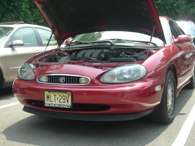 Red Mercury Sable with hood open, showing engine. Another car is parked next to it