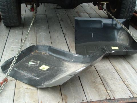 1985 Ford Bronco - Vehicle floor pans are shown on wooden planks, secured by chains to an unseen vehicle.