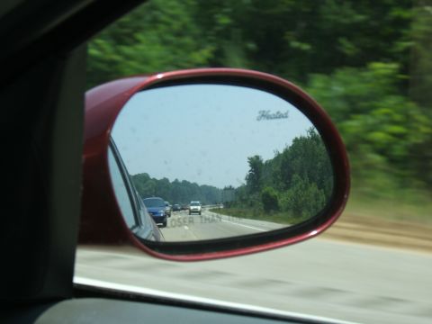 1998 Ford Taurus - View of highway traffic in a red car's side mirror, with the common warning text visible.