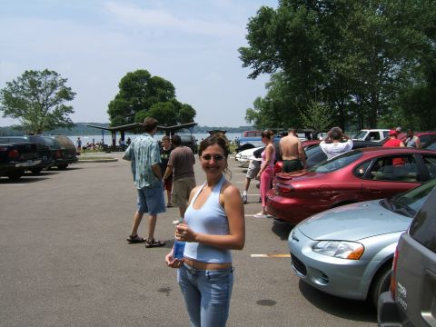 1998 Ford Taurus - People gather in a parking lot near a lake on a sunny day, with several cars visible.