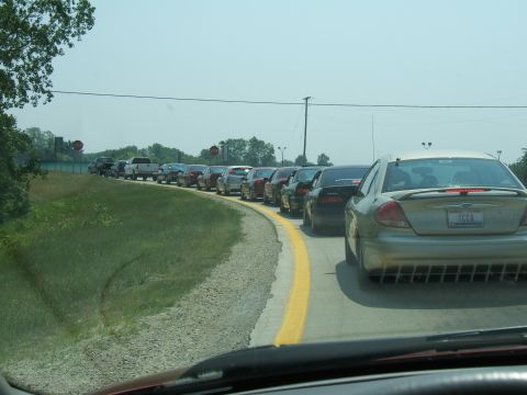 1998 Ford Taurus - A line of cars is backed up on a sunny day, with a gold sedan prominently in the foreground.