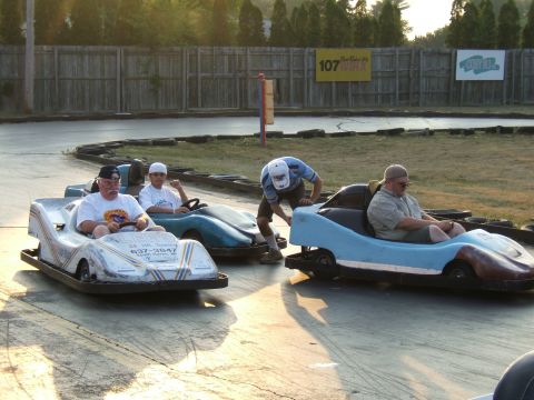 1998 Ford Taurus - Go-karts race on a track with spectators watching from the sidelines.
