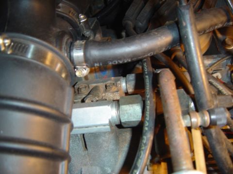 1986 Ford Bronco - Close-up view of engine compartment components, including hoses and metal fittings.