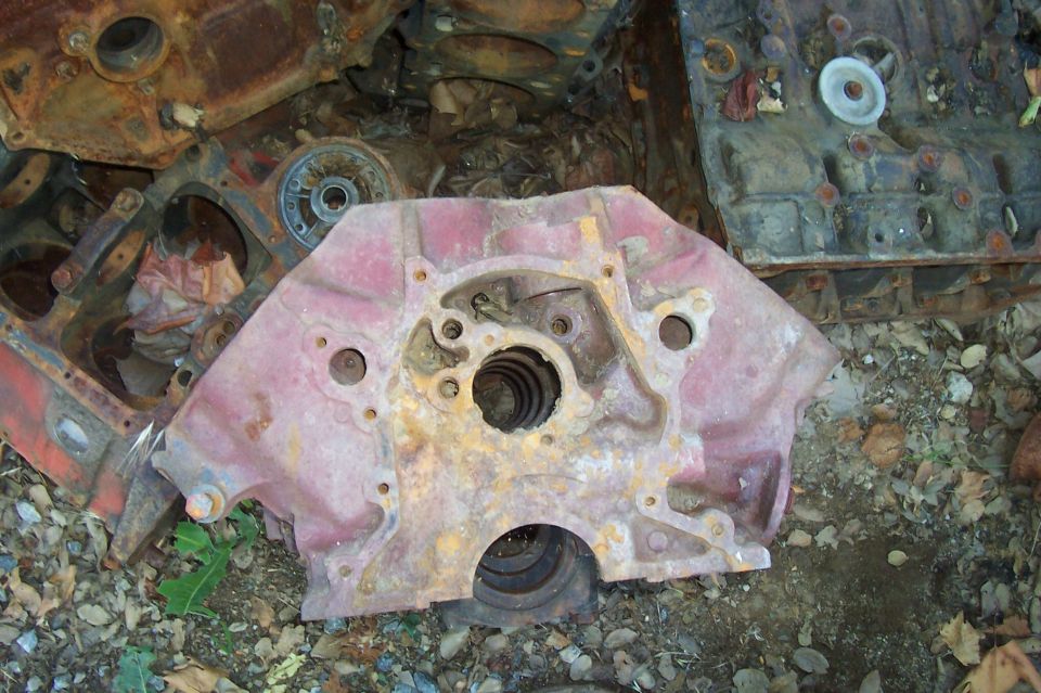 pile of old, rusty engine blocks and parts on the ground