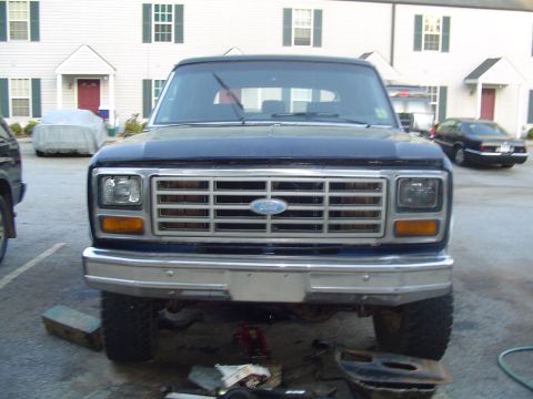 1982 Ford Bronco - Front view of a dark blue Ford Bronco, a prominent chrome grille and rectangular headlights.
