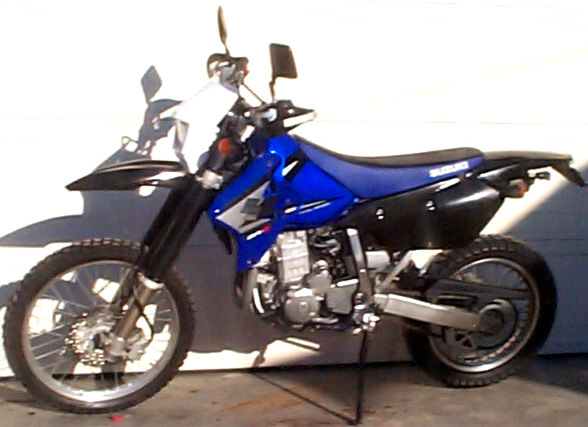 2005 Suzuki DR-Z400S dual-sport motorcycle parked in front of a garage door