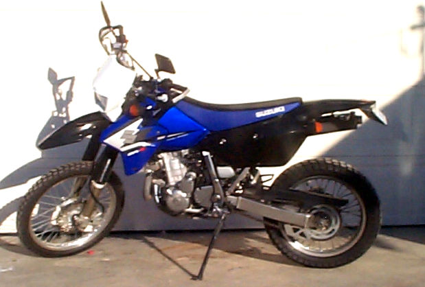 Blue and black Suzuki DR-Z400S motorcycle parked on a concrete surface, side view