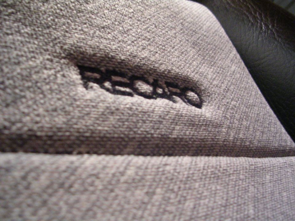 Close-up of a gray cloth seat with embroidered RECARO logo