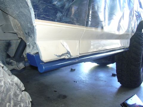 1991 Ford Bronco - Aftermarket rock sliders are installed on the side of a vehicle, near the wheel well.
