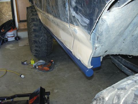 1991 Ford Bronco - Vehicle bodywork and new blue rock sliders are shown during installation, with tools on the floor.
