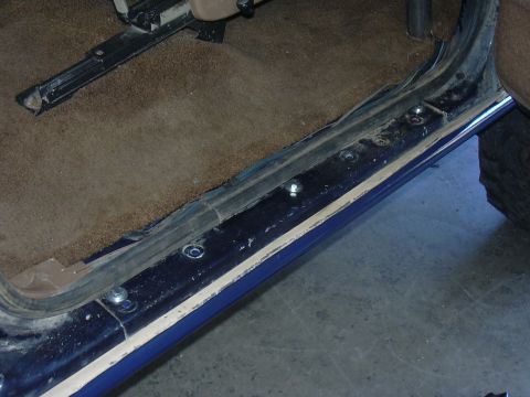 1991 Ford Bronco - Close-up view of the interior door sill and carpet of a vehicle.